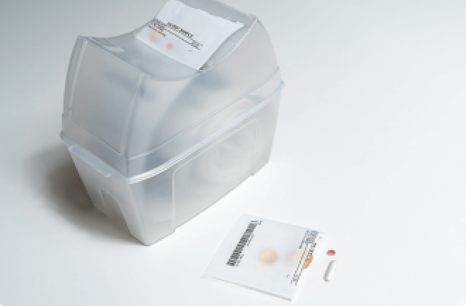 Daily dose medication dispenser — translucent plastic box with pre-packaged sachets on a clean surface